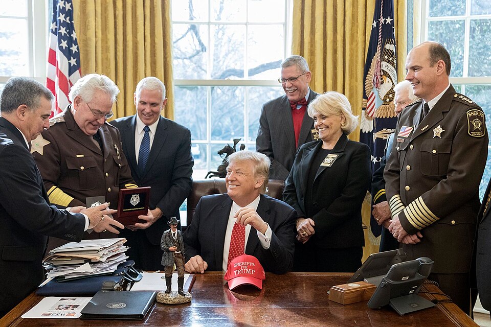 President Donald Trump laughing with sheriffs in the Oval Office in 2017